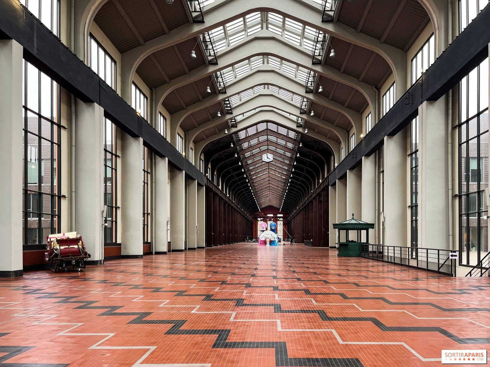 Nef de la Cité du Cinéma à Saint-Denis, longue verrière et carrelage rouge en enfilade, vue de jour