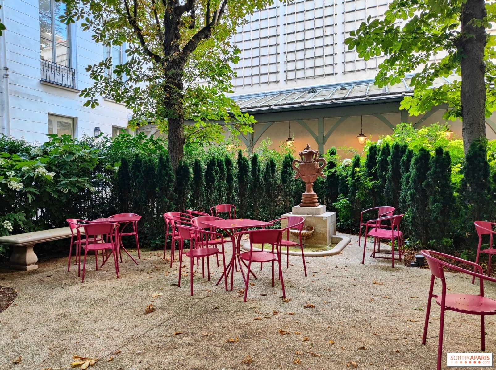 La cour pavée de la Maison Victor Hugo, ses tables rouges et sa fontaine sous les arbres