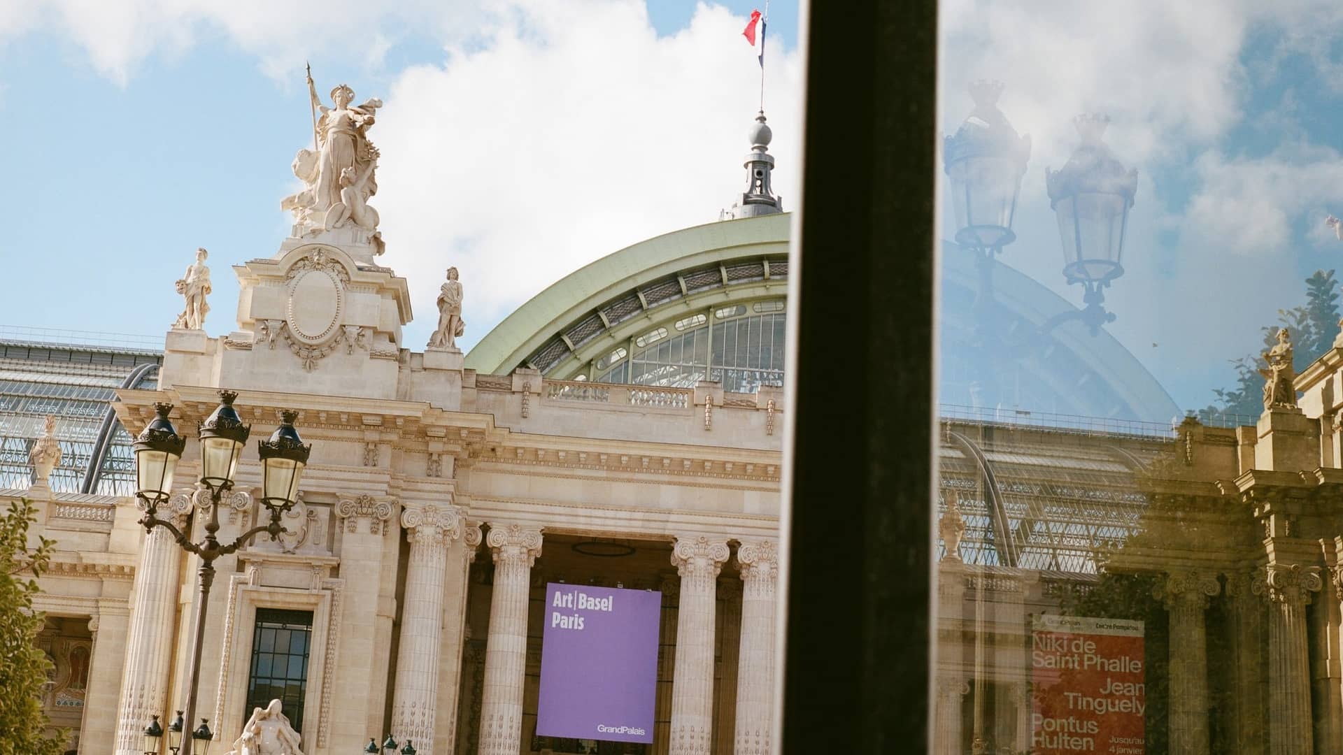 Façade du Grand Palais avec la bannière violette Art Basel Paris entre les colonnes, vue à travers une vitre