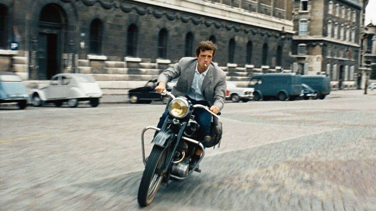Jean-Paul Belmondo à moto, cigarette aux lèvres, dans une rue de Paris dans L'Homme de Rio
