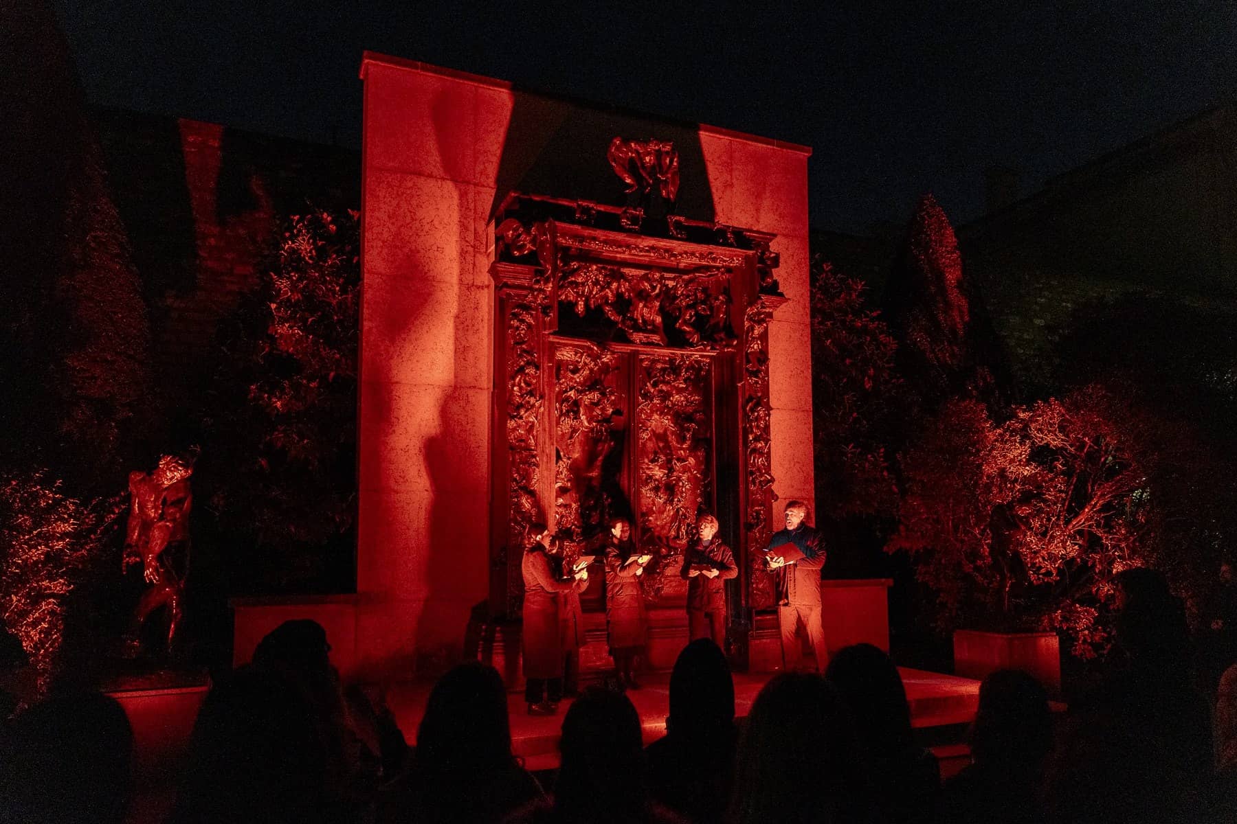 Actors lit in red in front of Rodin's Gates of Hell during the 2025 Bienvenue en Enfer evening