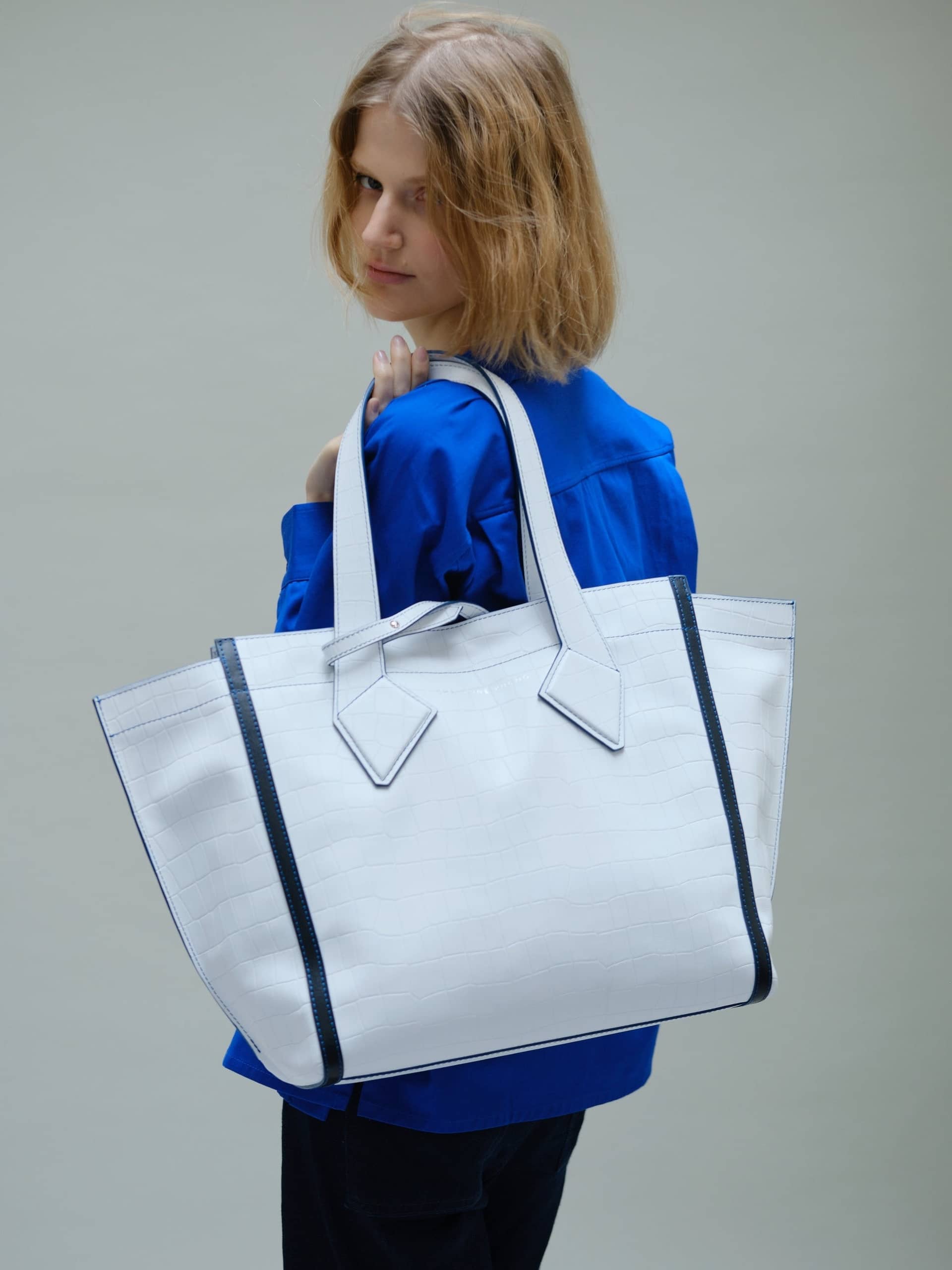 Sac cabas en cuir blanc façon croco de Christine Phung tenu à bout de bras