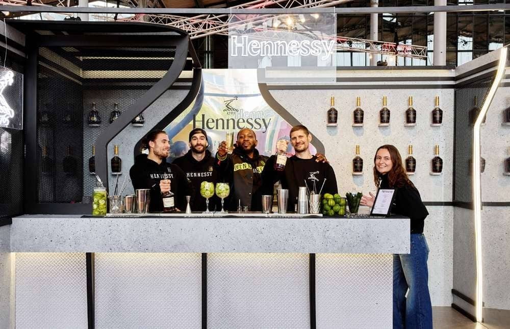 L'équipe du bar Hennessy alignée derrière son comptoir sous la charpente de la Grande Halle