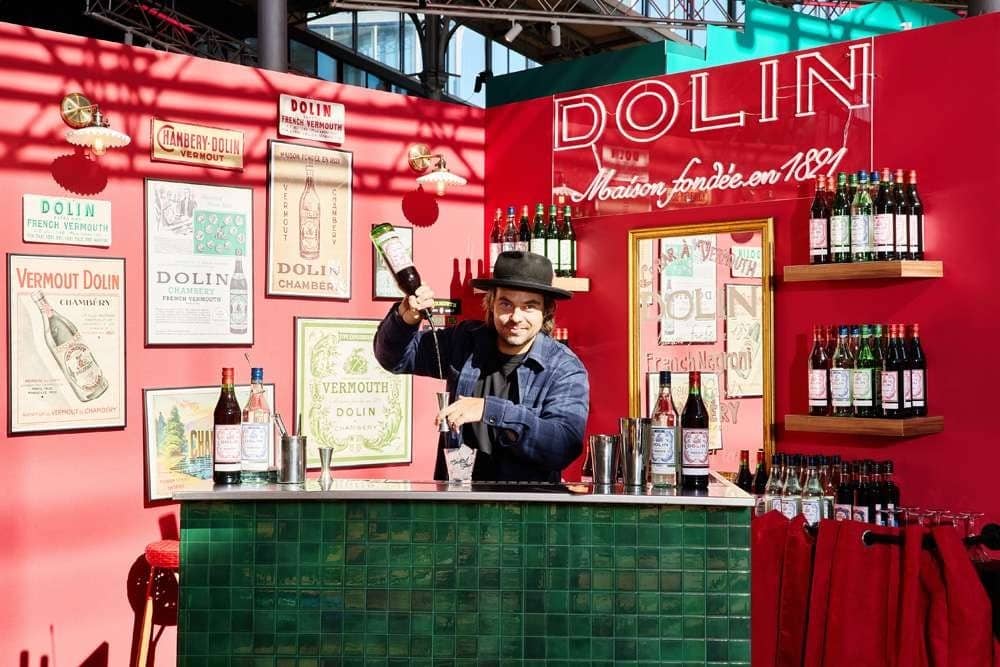 Un bartender secoue son shaker derrière le bar Dolin rose et carrelé de vert à Cocktail Street
