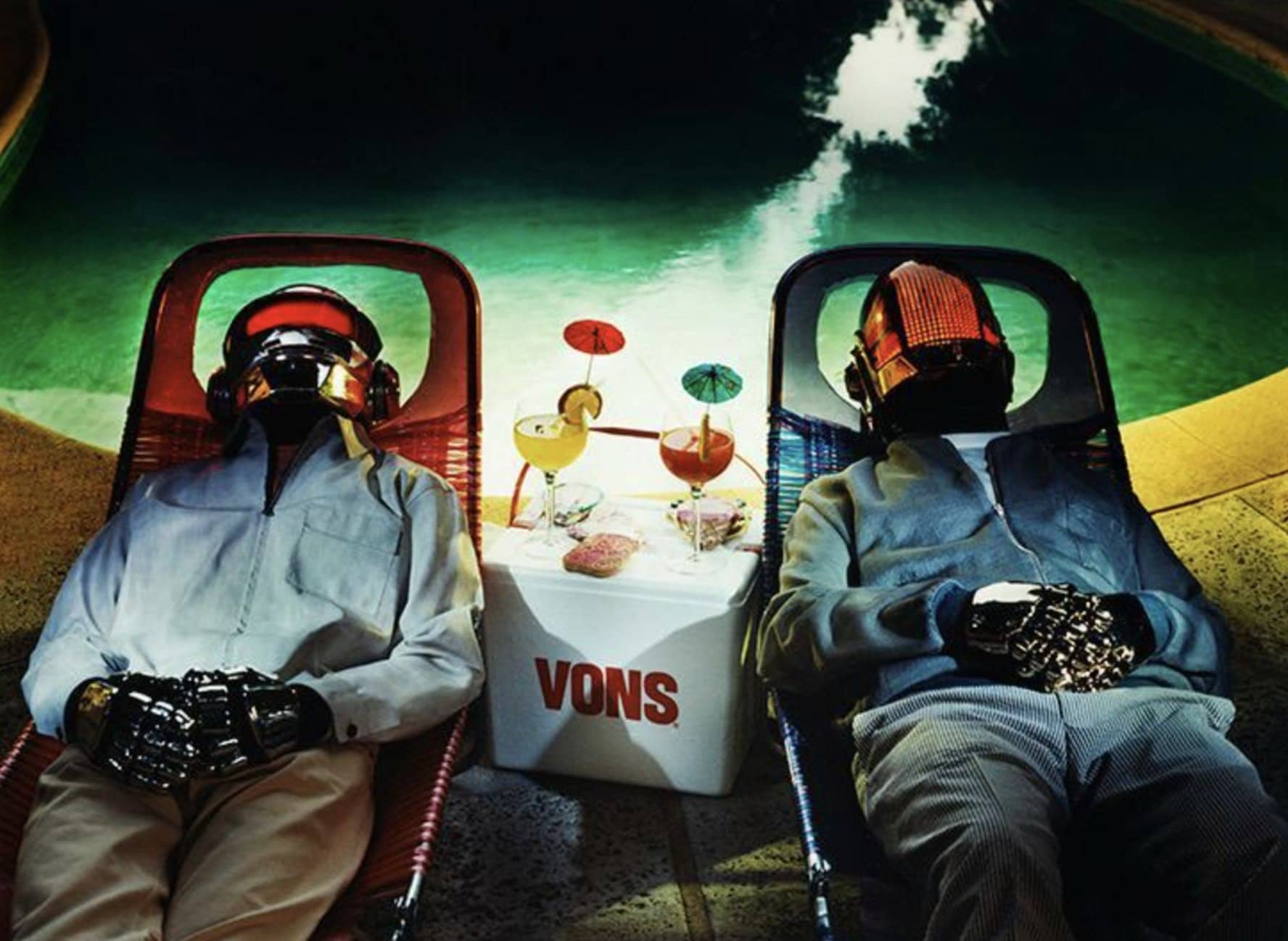 Les Daft Punk casqués allongés sur des transats au bord d'une piscine, cocktails posés entre eux