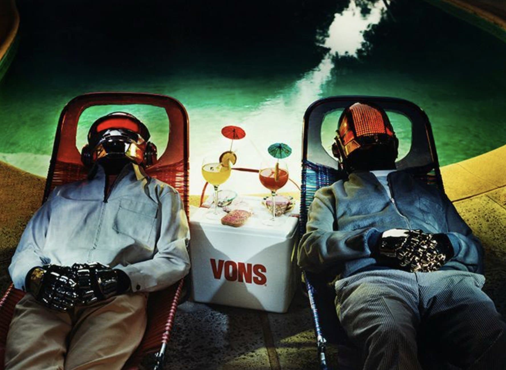 Les Daft Punk casqués allongés sur des transats au bord d'une piscine, cocktails posés entre eux