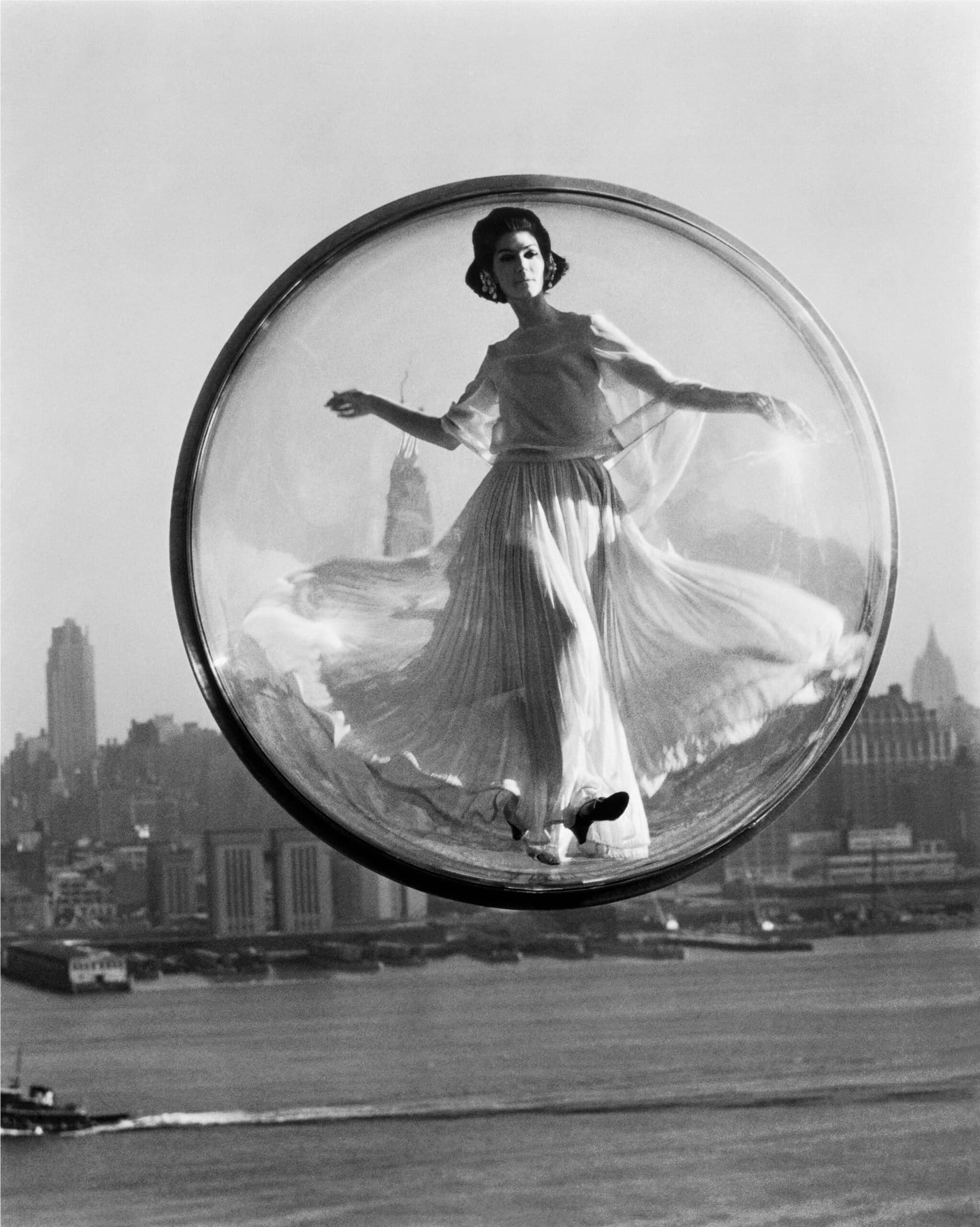 Femme en robe flottant dans une bulle transparente au-dessus des gratte-ciels de New York