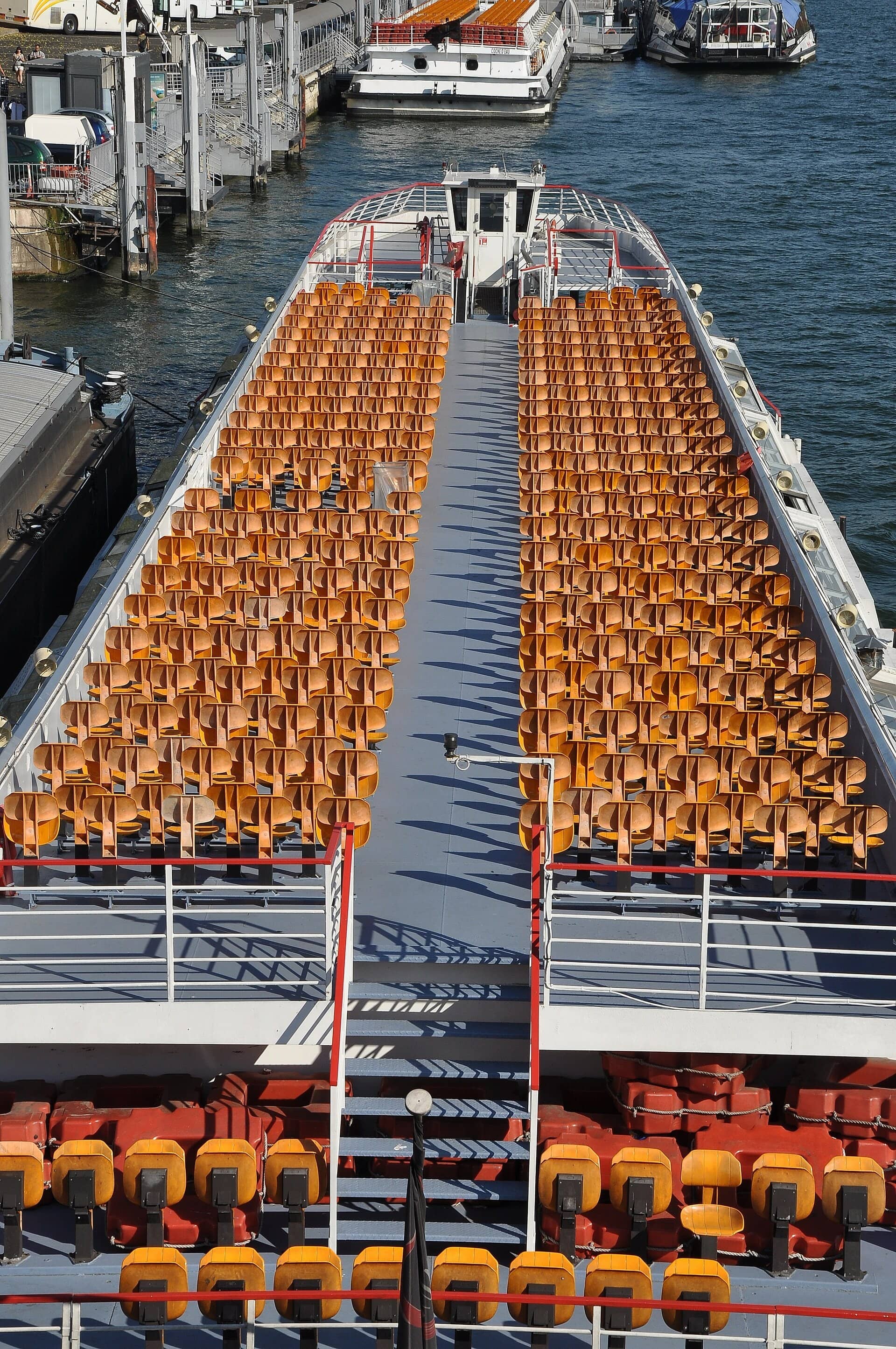 Pont supérieur d'un bateau-mouche aux sièges orange, à quai au port de la Conférence près du pont de l'Alma