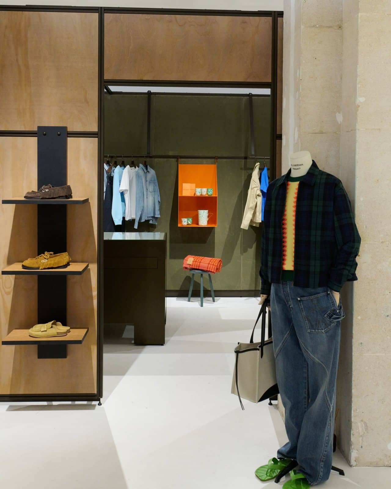 Intérieur du pop-up JW Anderson, mannequin, étagères en bois clair et portants de vêtements