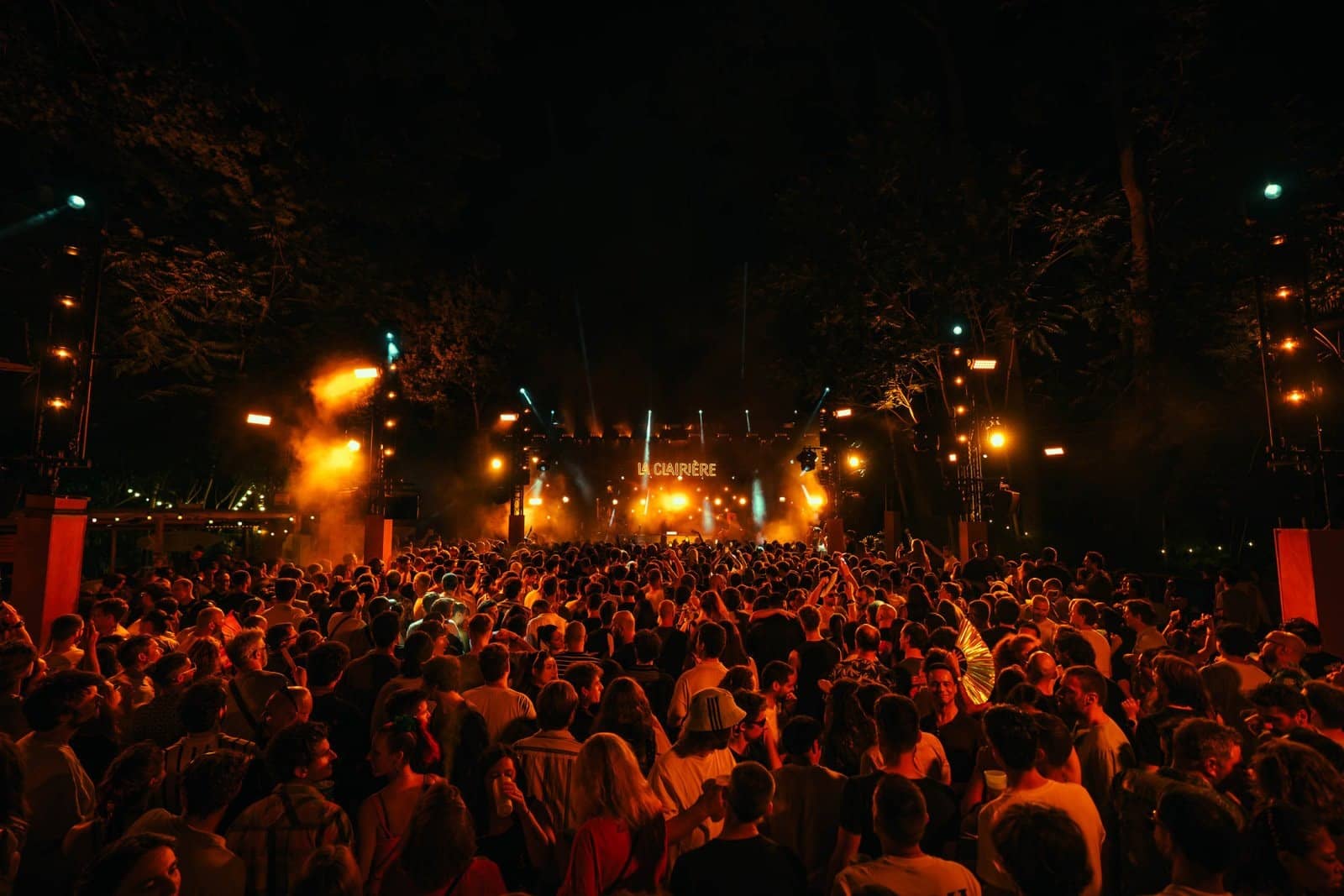 Foule dense sous les guirlandes lumineuses et les arbres du domaine de Longchamp la nuit