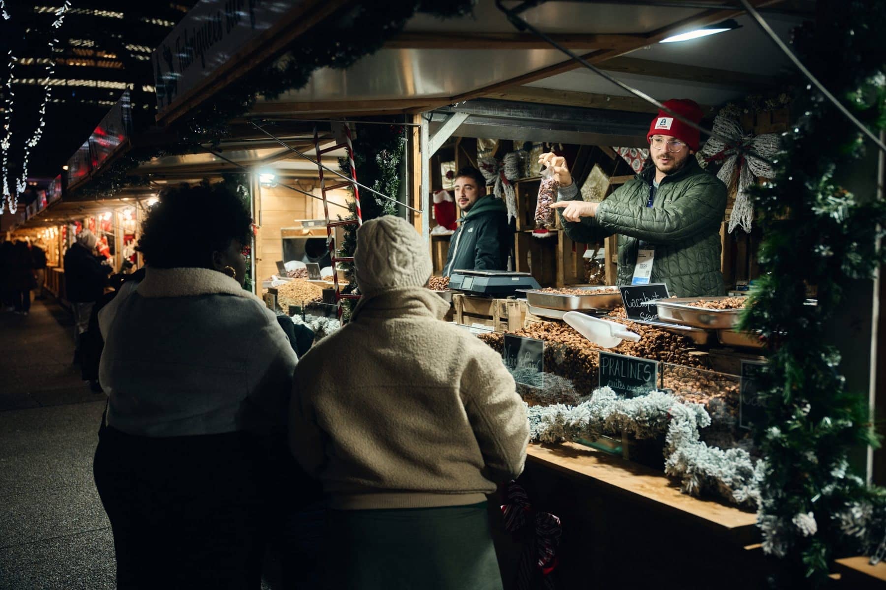 Un commerçant sert des visiteuses devant son chalet garni de sapin au marché de Noël de La Défense