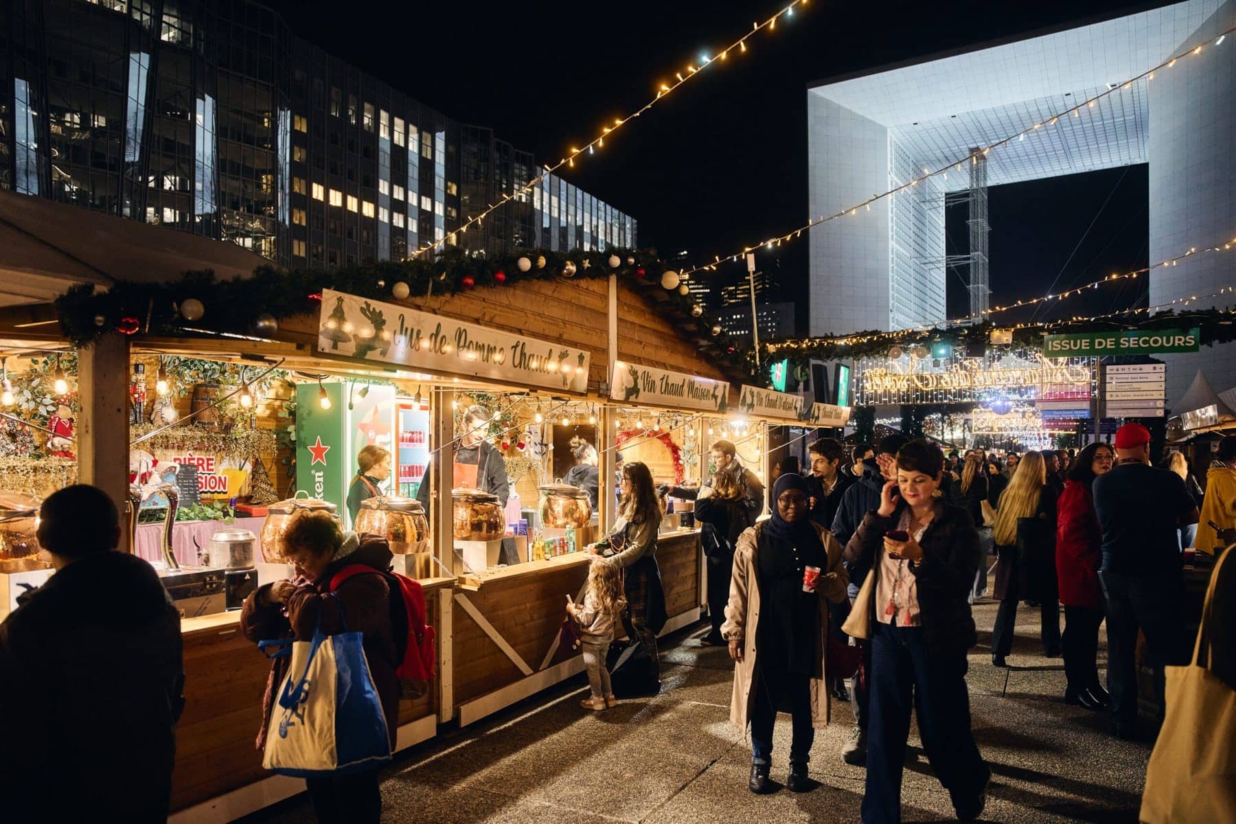 Allée de chalets en bois décorés du marché de Noël, la Grande Arche de La Défense au bout