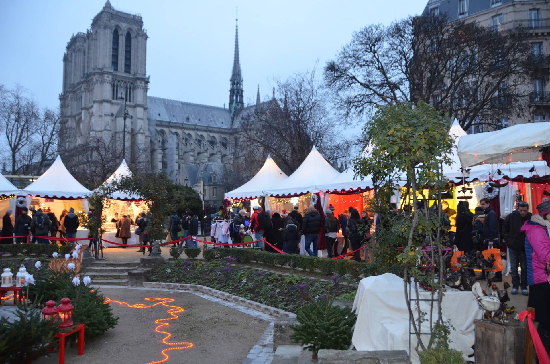 Les tentes blanches du marché de Noël de Notre-Dame entre les sapins du square René Viviani