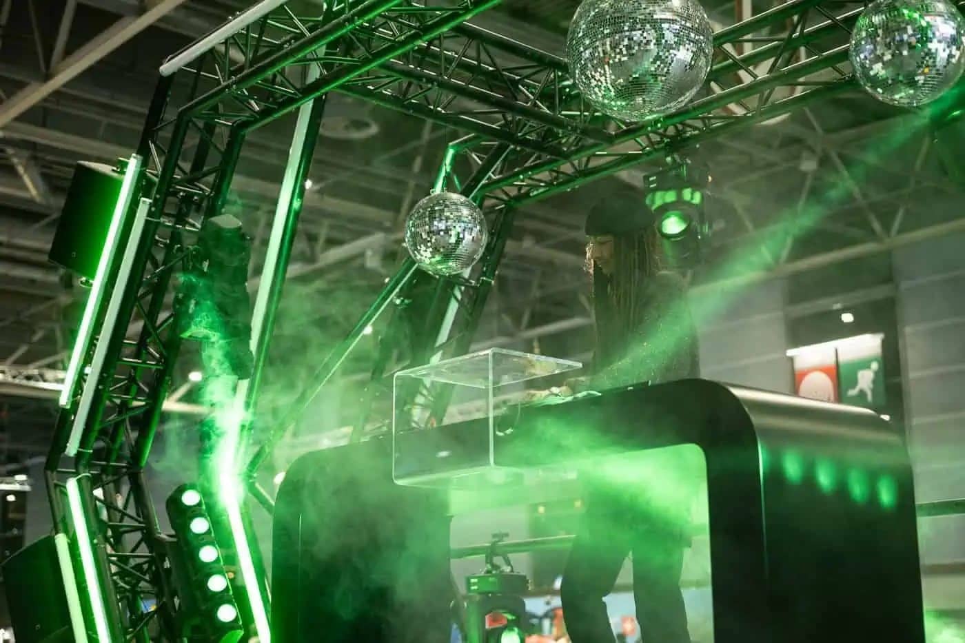 DJ aux platines sous des boules à facettes et des lumières vertes pendant une nocturne du Mondial de l'Auto