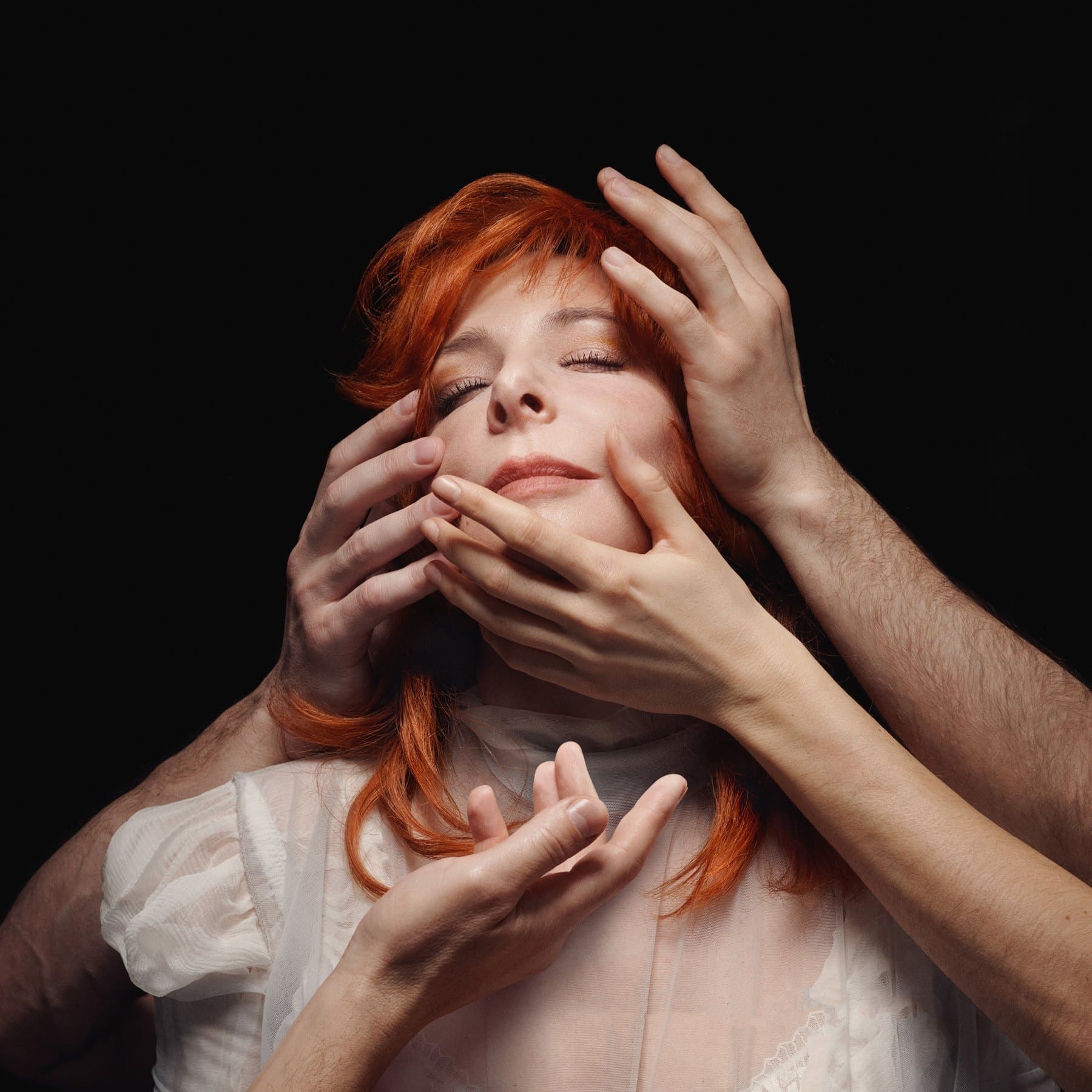 Égrégore album cover: Mylène Farmer, red hair, eyes closed, her face held by several hands on a black background