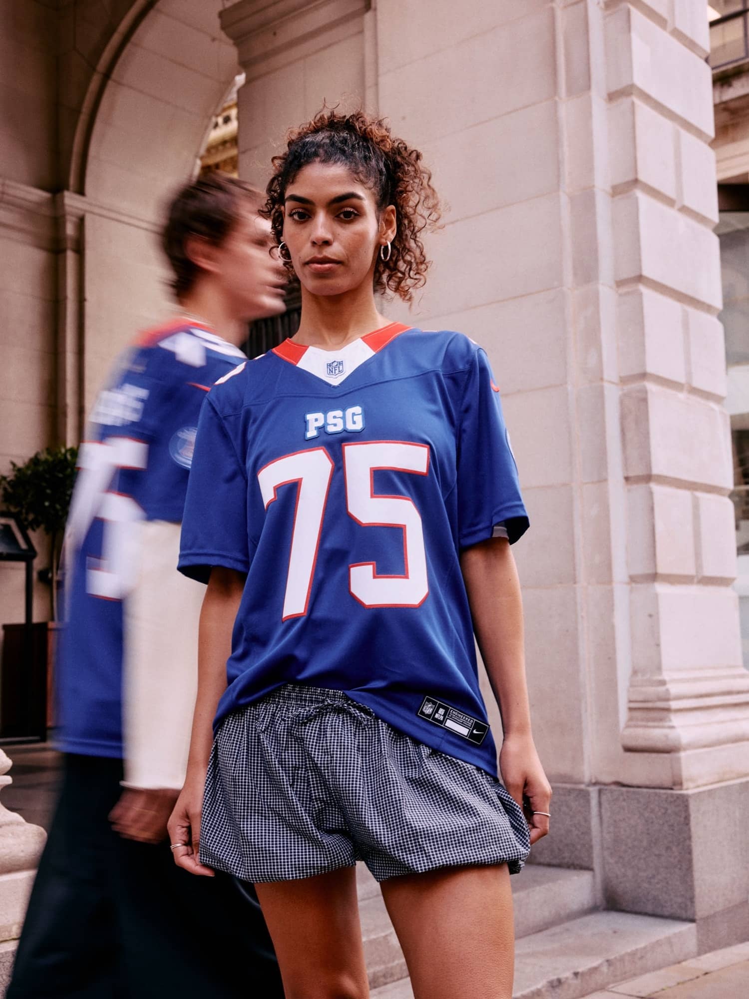 Maillot bleu NFL x PSG floqué 75 porté devant une façade en pierre