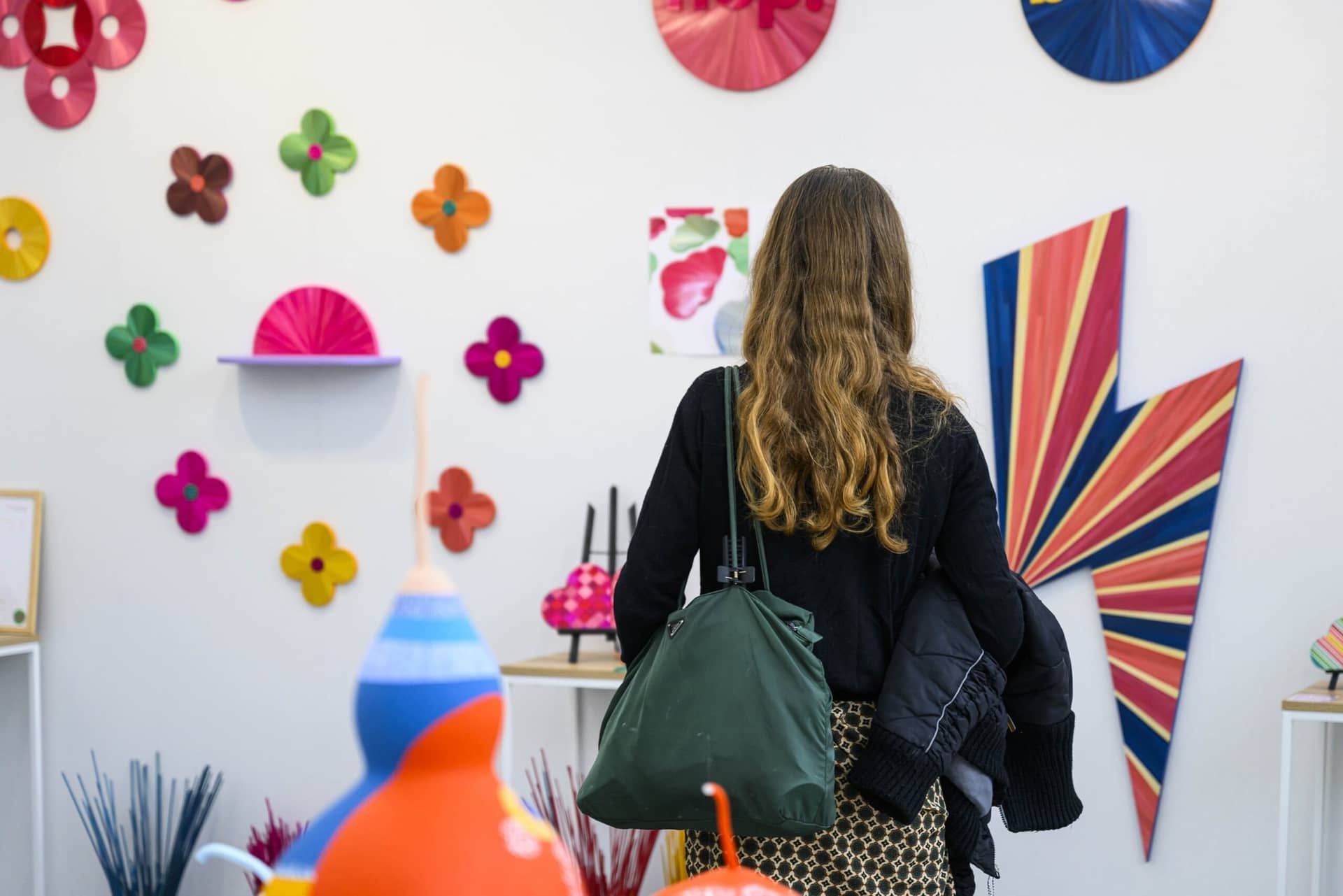 Mur de fleurs et d'éclairs en papier coloré sur le stand HOP Studio, une visiteuse de dos