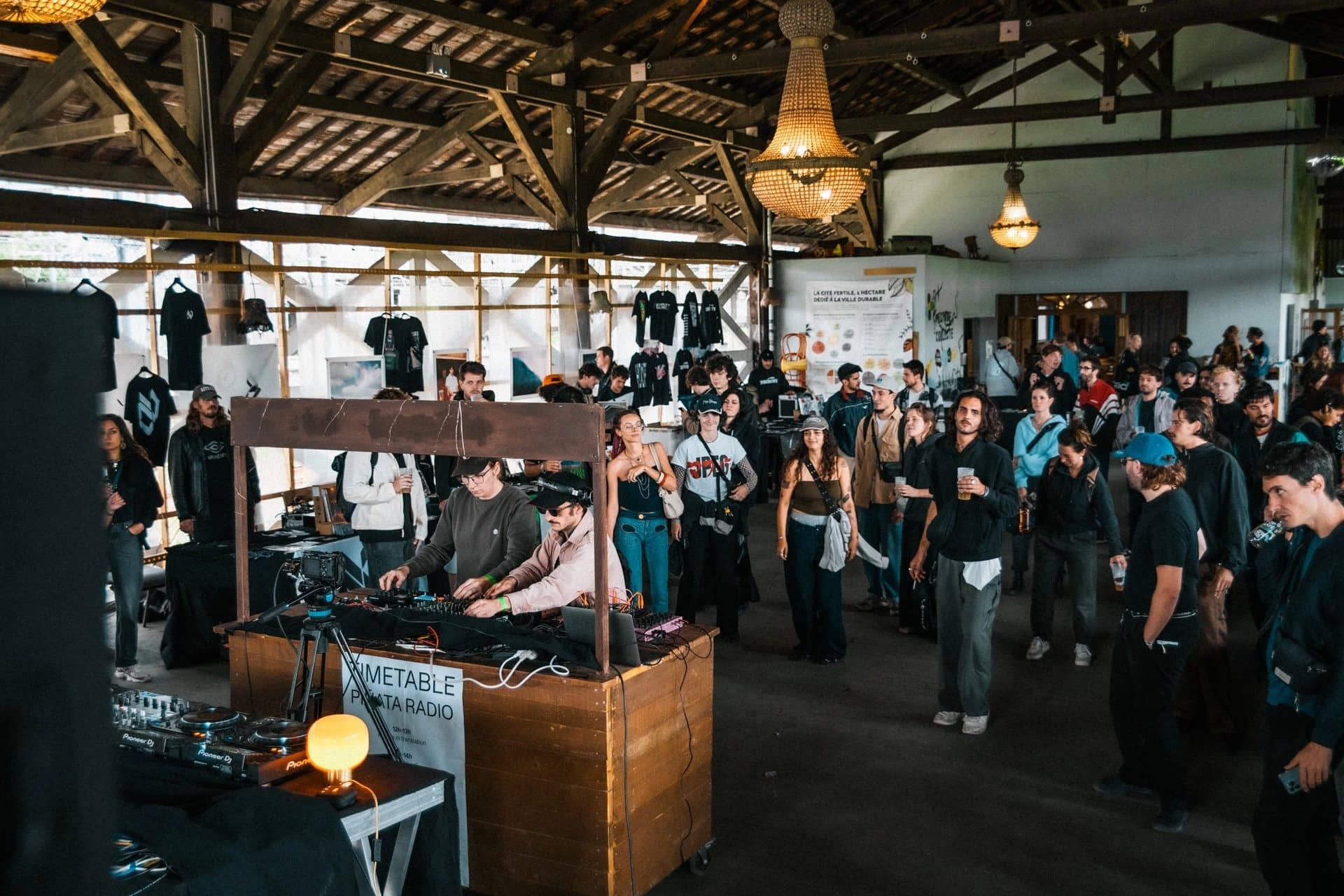 DJ set devant la foule sous la charpente en bois d'une friche, édition précédente de la Paris Electronic Week