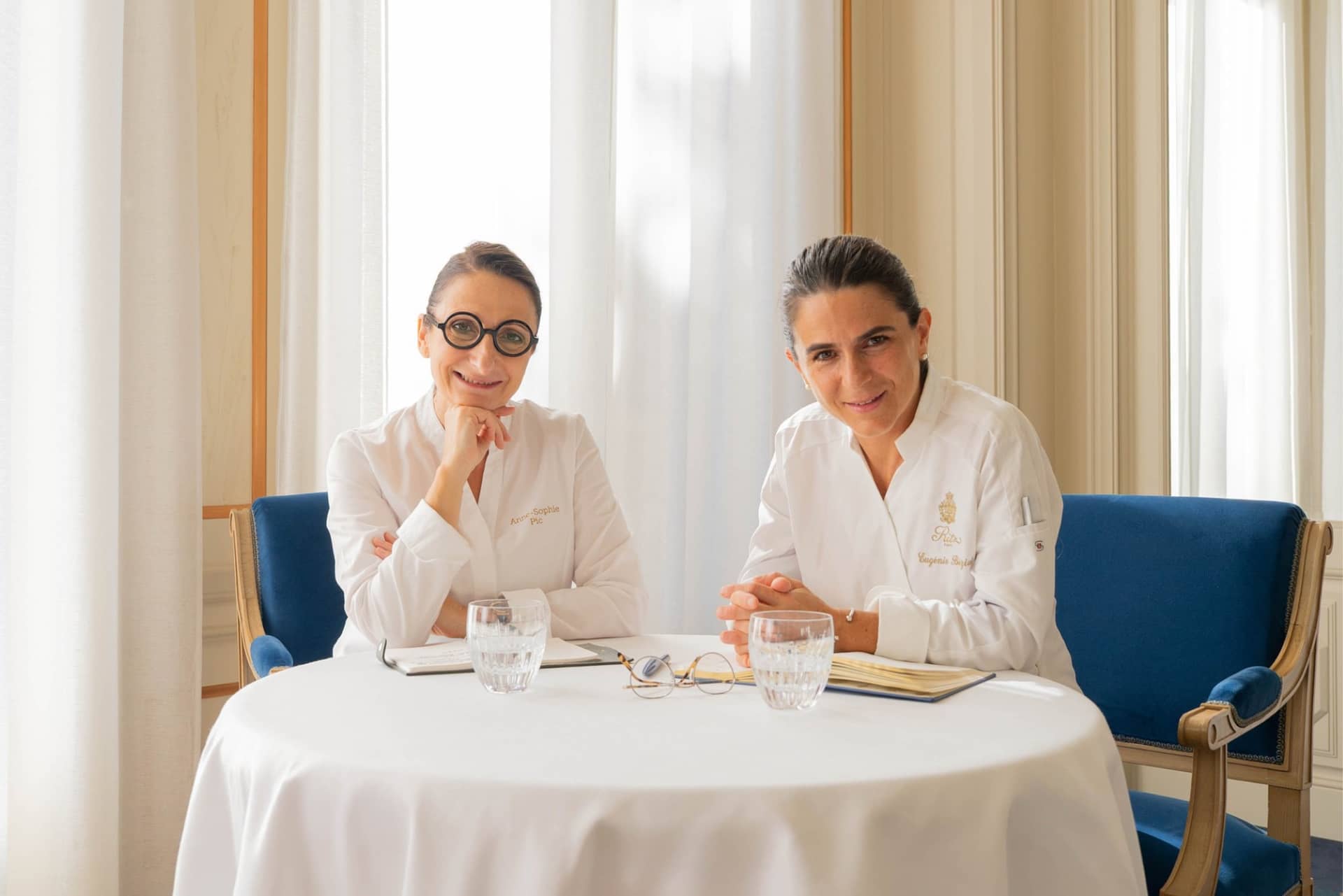 Anne-Sophie Pic et Eugénie Béziat en veste blanche, assises côte à côte à une table de l'Espadon