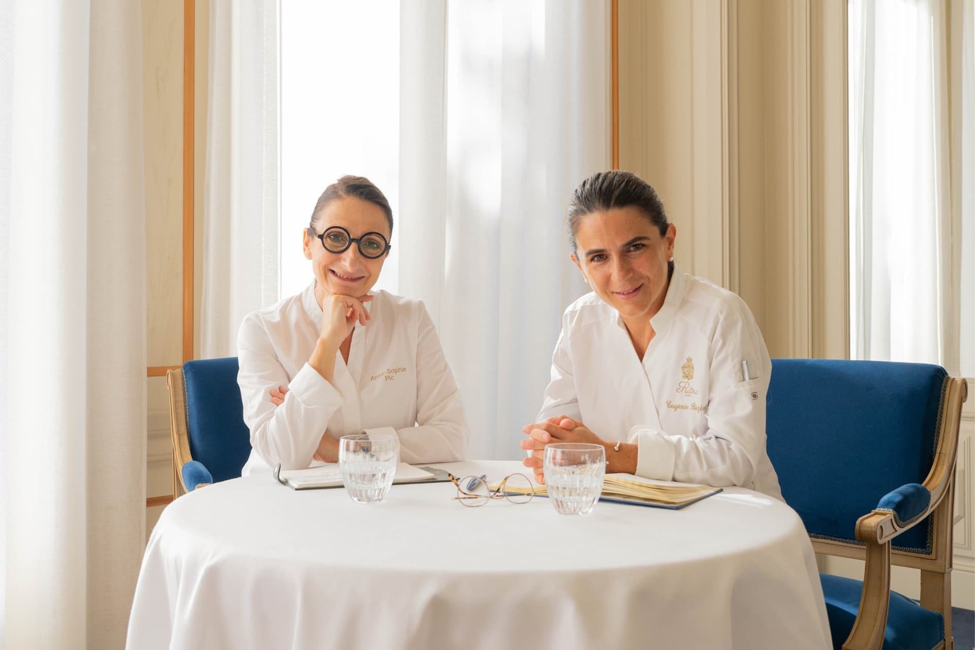 Anne-Sophie Pic et Eugénie Béziat en veste blanche, assises côte à côte à une table de l'Espadon