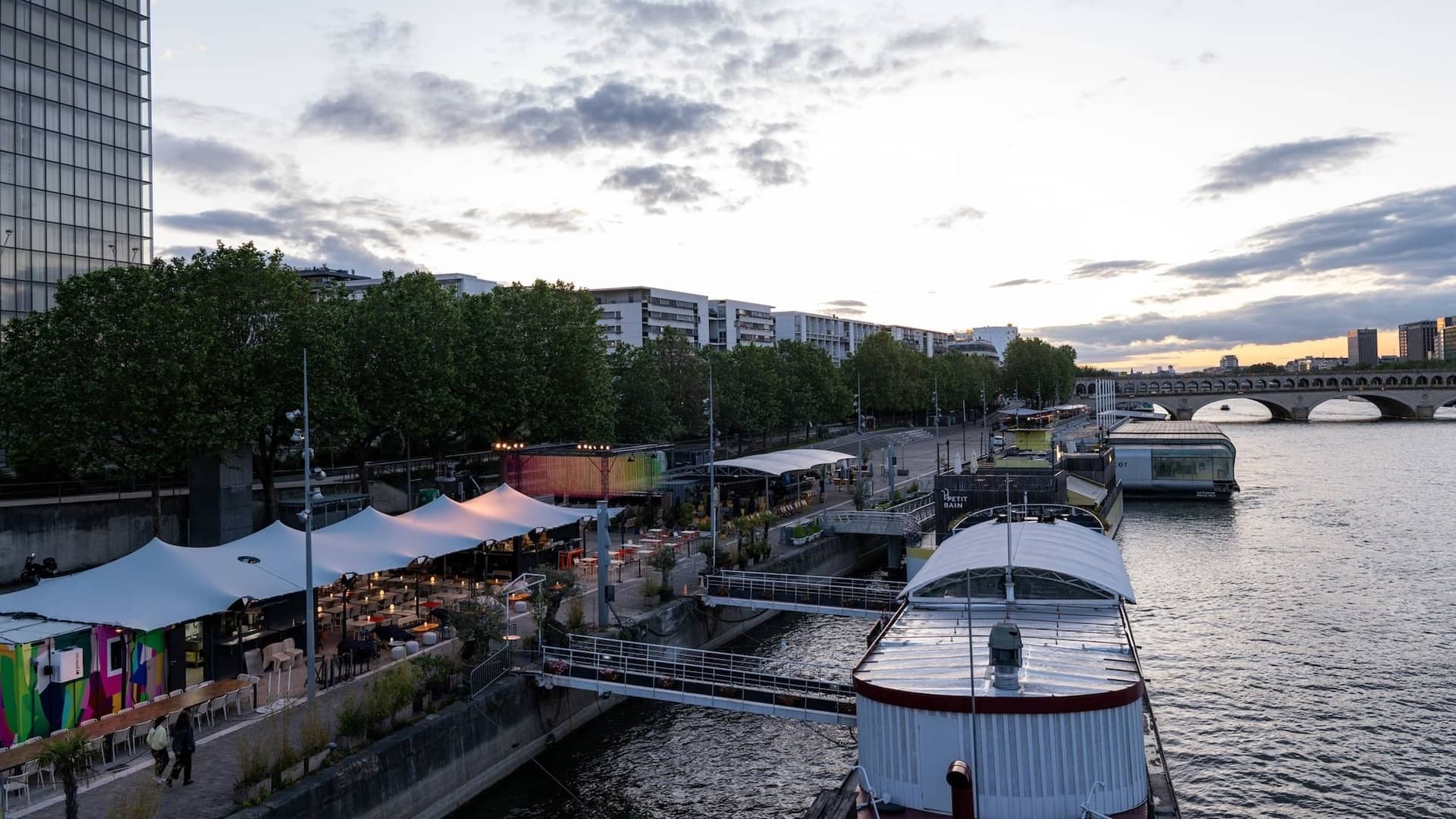 Tentes blanches de PLAT/FORM alignées sur les quais de la Seine au coucher du soleil, BnF en arrière-plan
