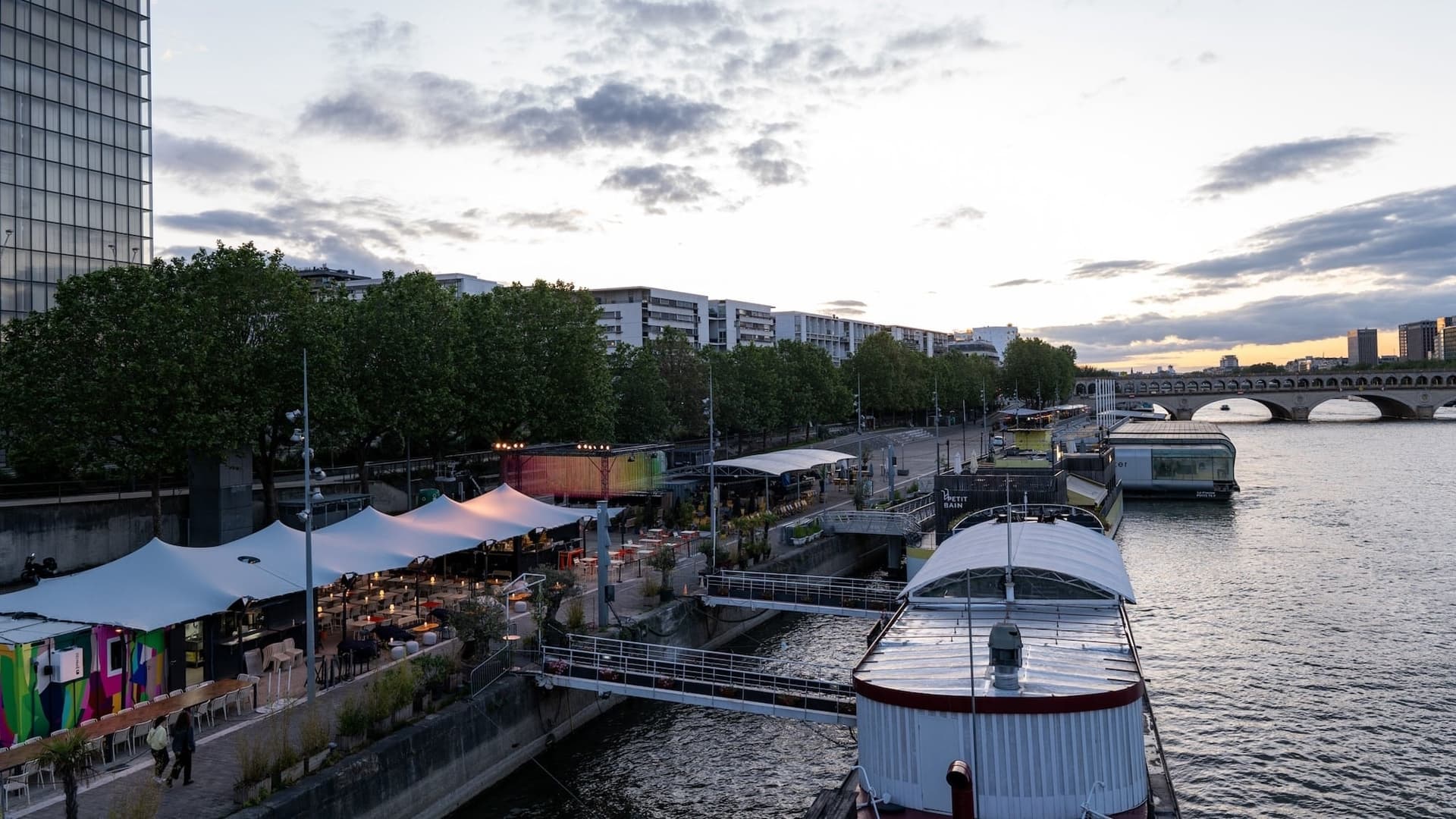 Tentes blanches de PLAT/FORM alignées sur les quais de la Seine au coucher du soleil, BnF en arrière-plan