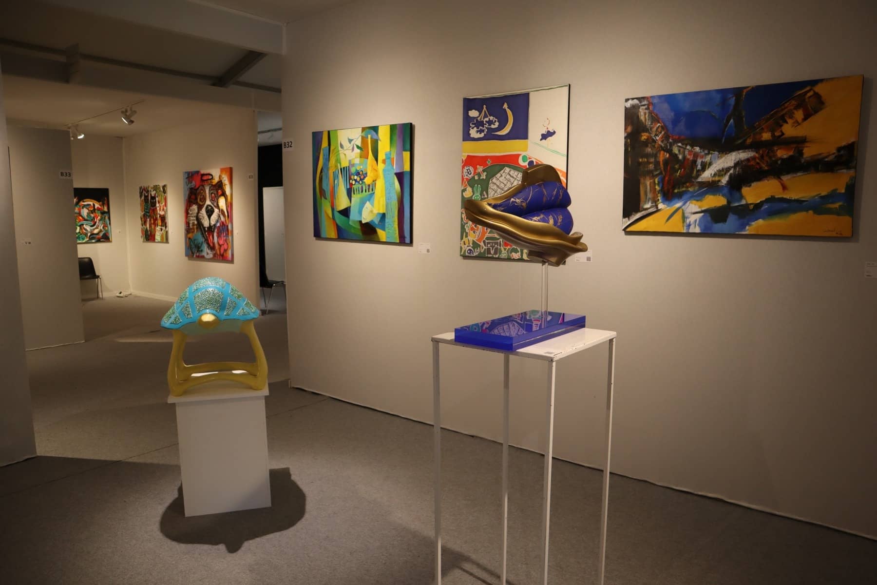 Tableaux colorés et sculptures sur socles blancs dans un stand du Salon d'Automne 2025