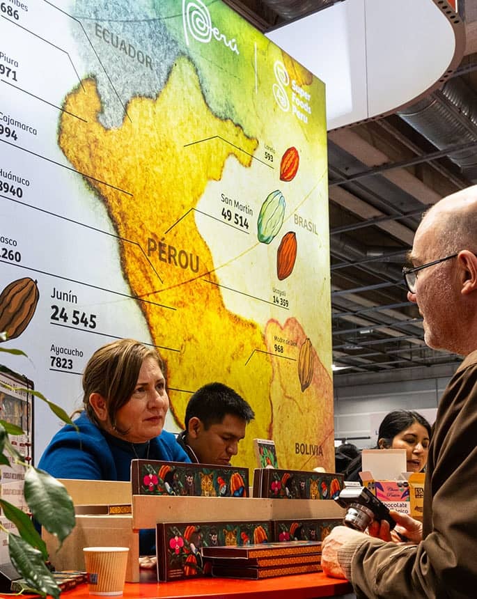 Visiteurs au stand d'un pays producteur de cacao, carte des régions du Pérou au mur, au Salon du Chocolat