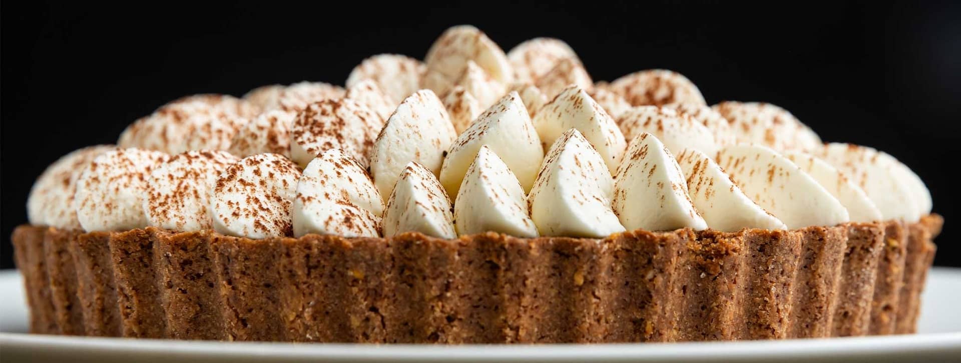 Tarte au chocolat couronnée de meringues saupoudrées de cacao, présentée au Pastry Show