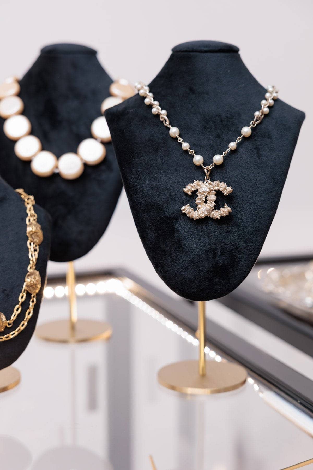Colliers Chanel en perles et strass présentés sur des bustes de velours bleu nuit