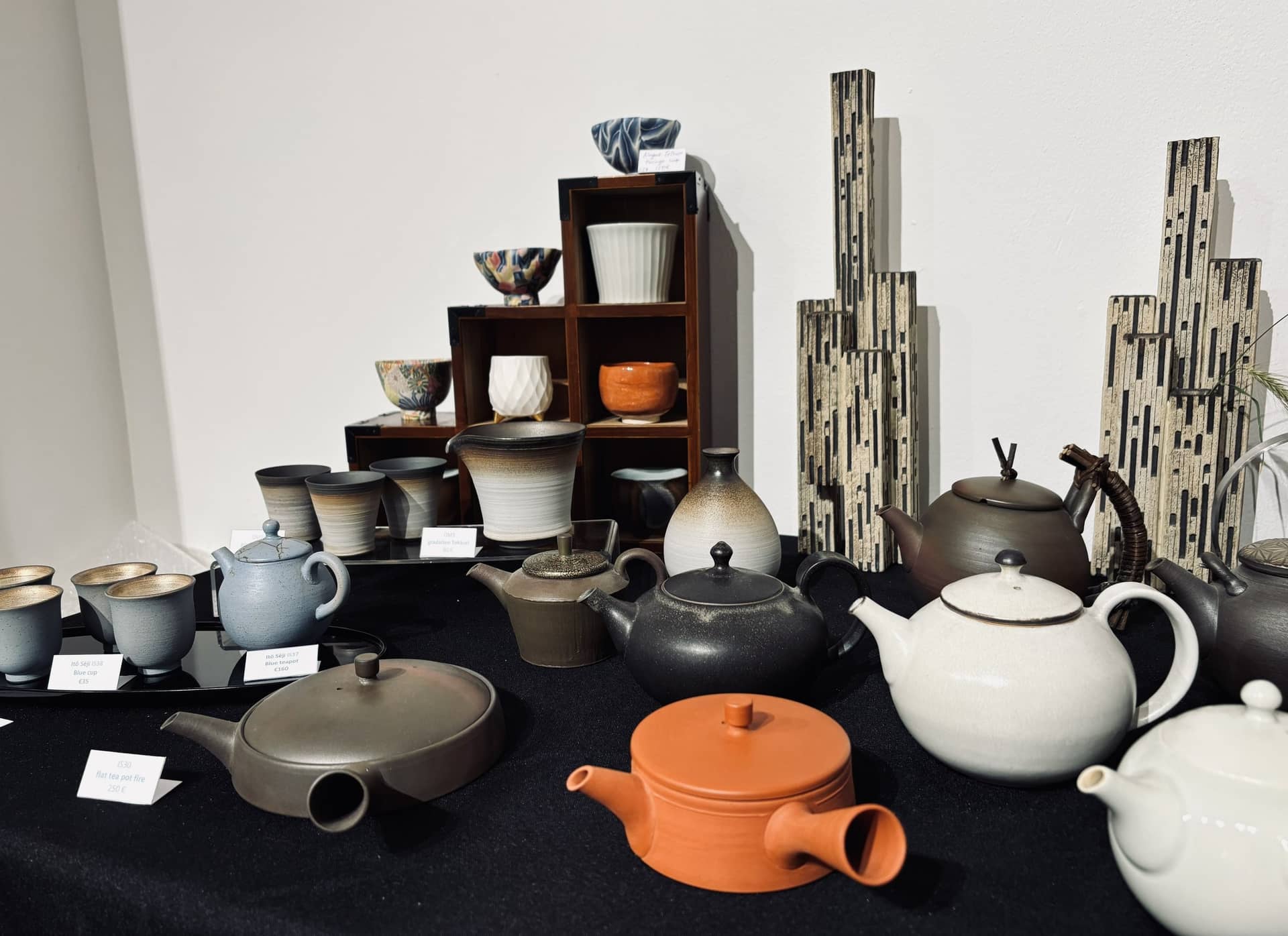 Théières en terre, bols et tasses d'une céramiste japonaise exposés sur une table noire du Salon Idées Japon