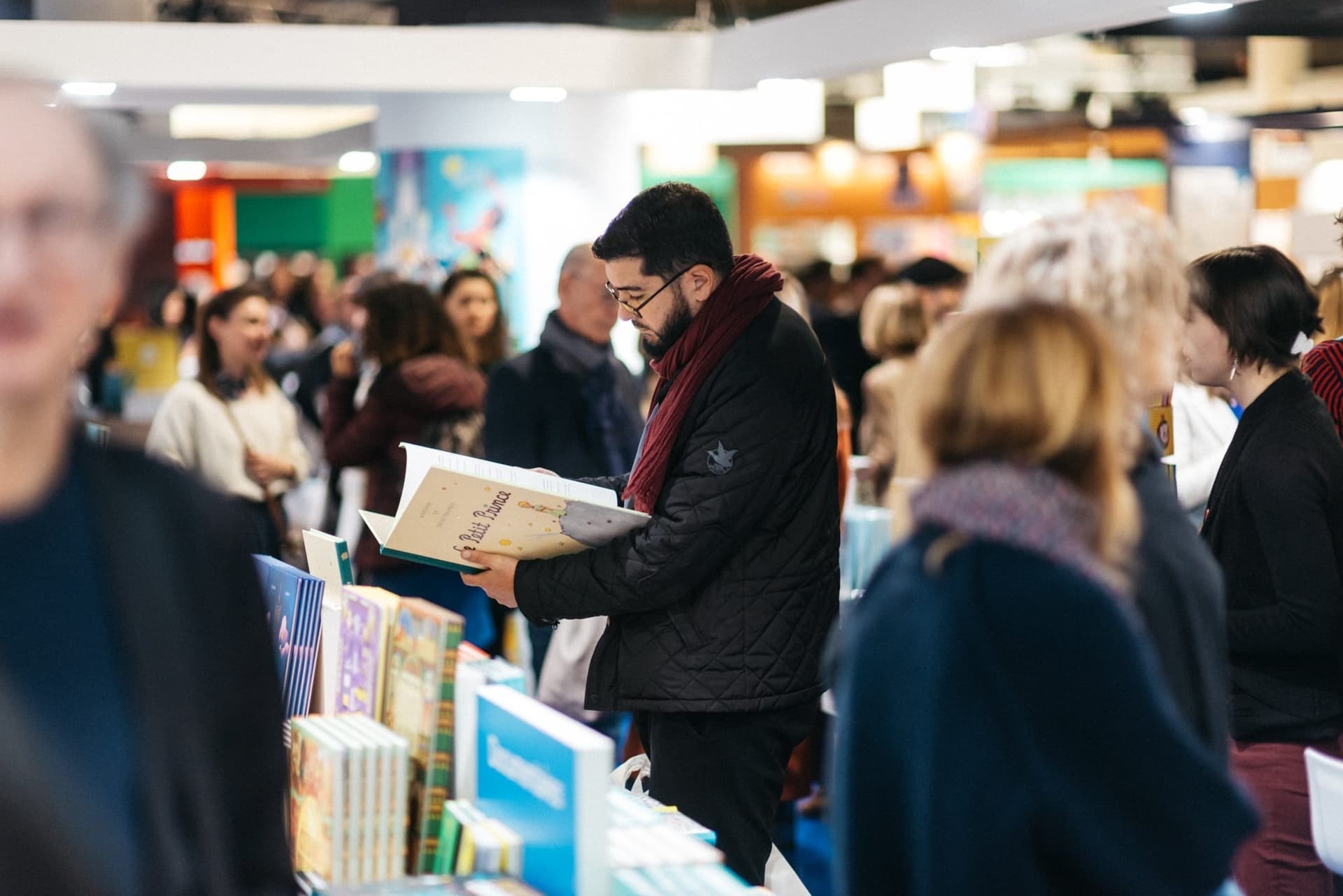 Un visiteur feuillette Le Petit Prince au milieu des stands du Salon du livre jeunesse de Montreuil