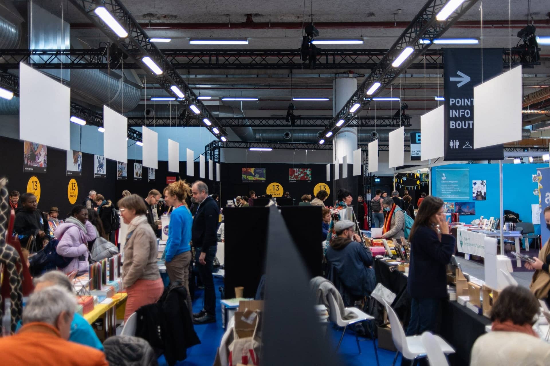 Allée de stands d'éditeurs sous la halle de Paris Montreuil Expo pendant le Salon du livre jeunesse