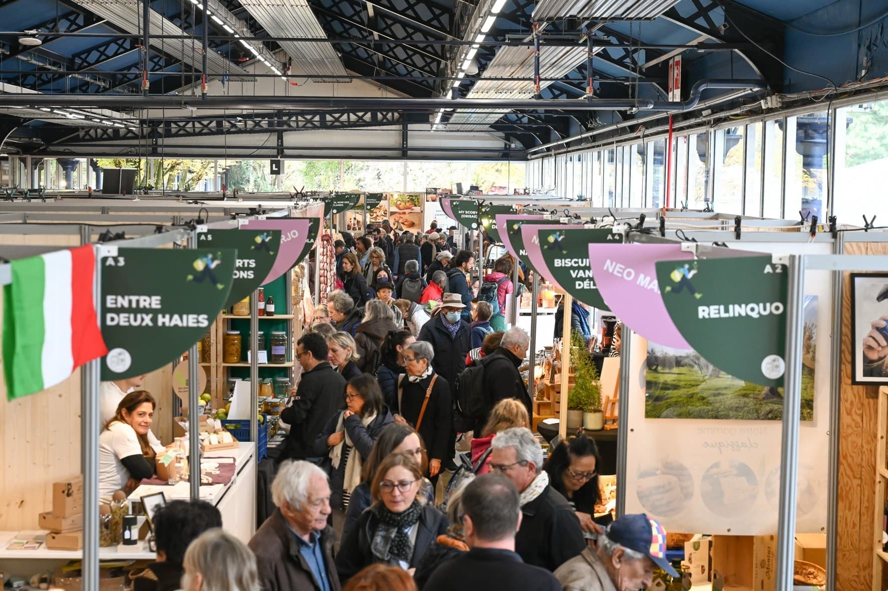 A packed aisle at Salon Marjolaine under the hall of Parc Floral, between the exhibitors' wooden stands