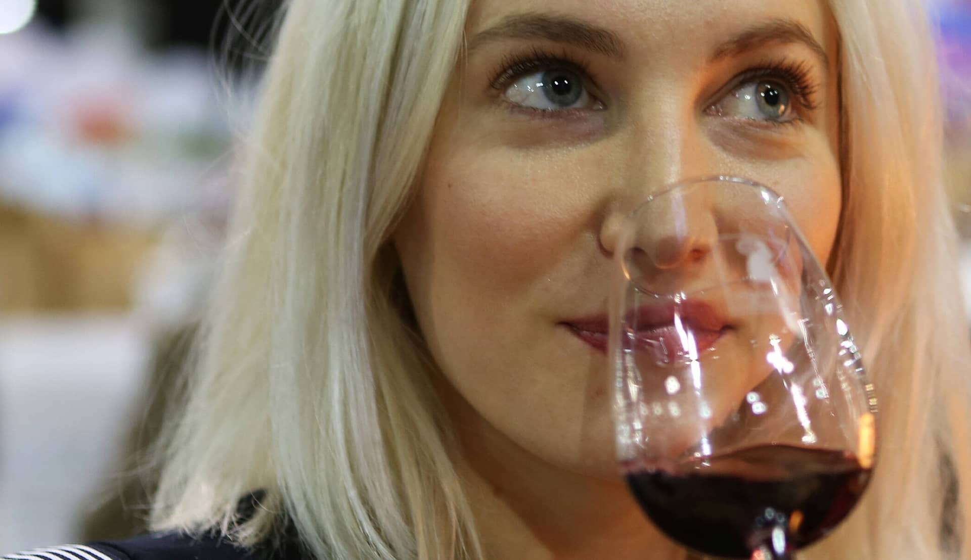 Une visiteuse sent un verre de vin rouge au milieu des allées d'un salon des Vignerons Indépendants