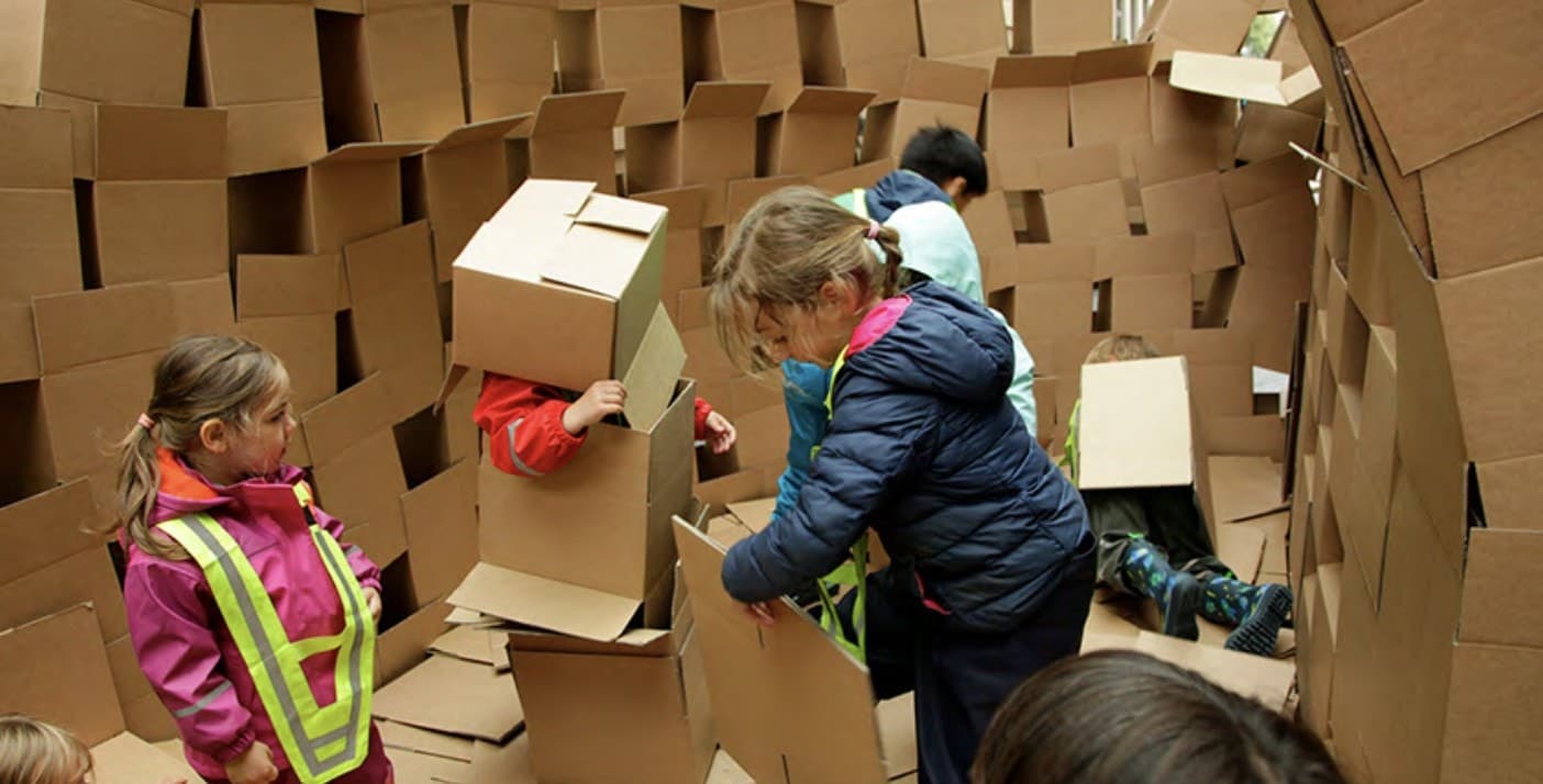 Des participants assemblent des briques de carton pour bâtir une cabane collective géante