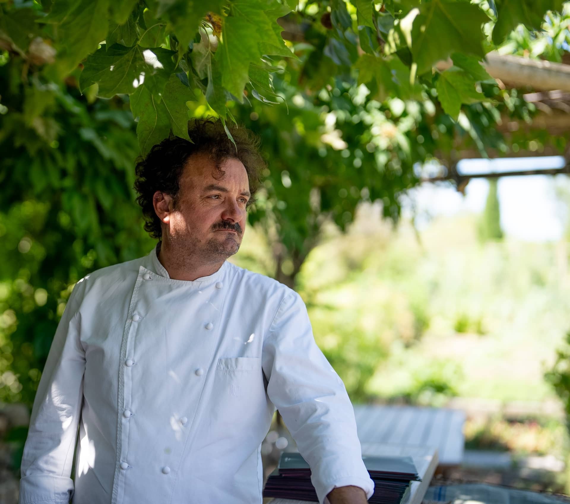 Le chef étoilé Armand Arnal, de La Chassagnette, en veste blanche dans un jardin sous une treille