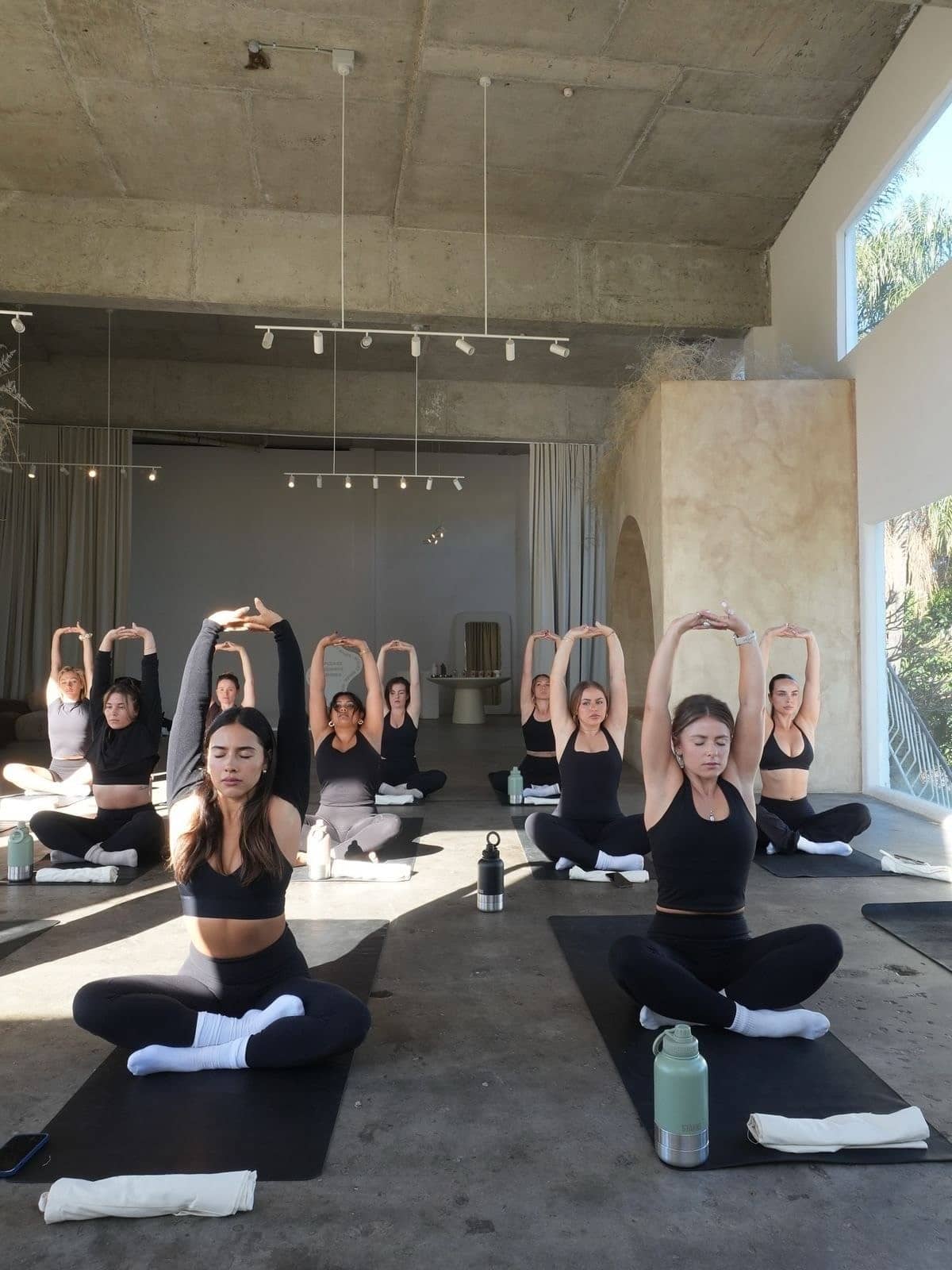 Cours de yoga collectif sur tapis dans une grande salle lumineuse pendant le festival