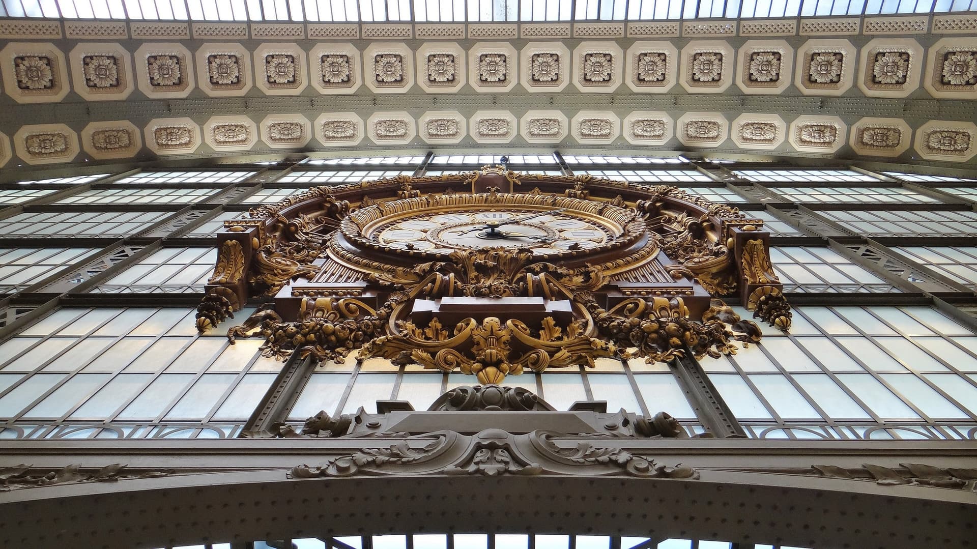 La grande horloge dorée de l'ancienne gare d'Orsay devant la verrière, vue de la nef