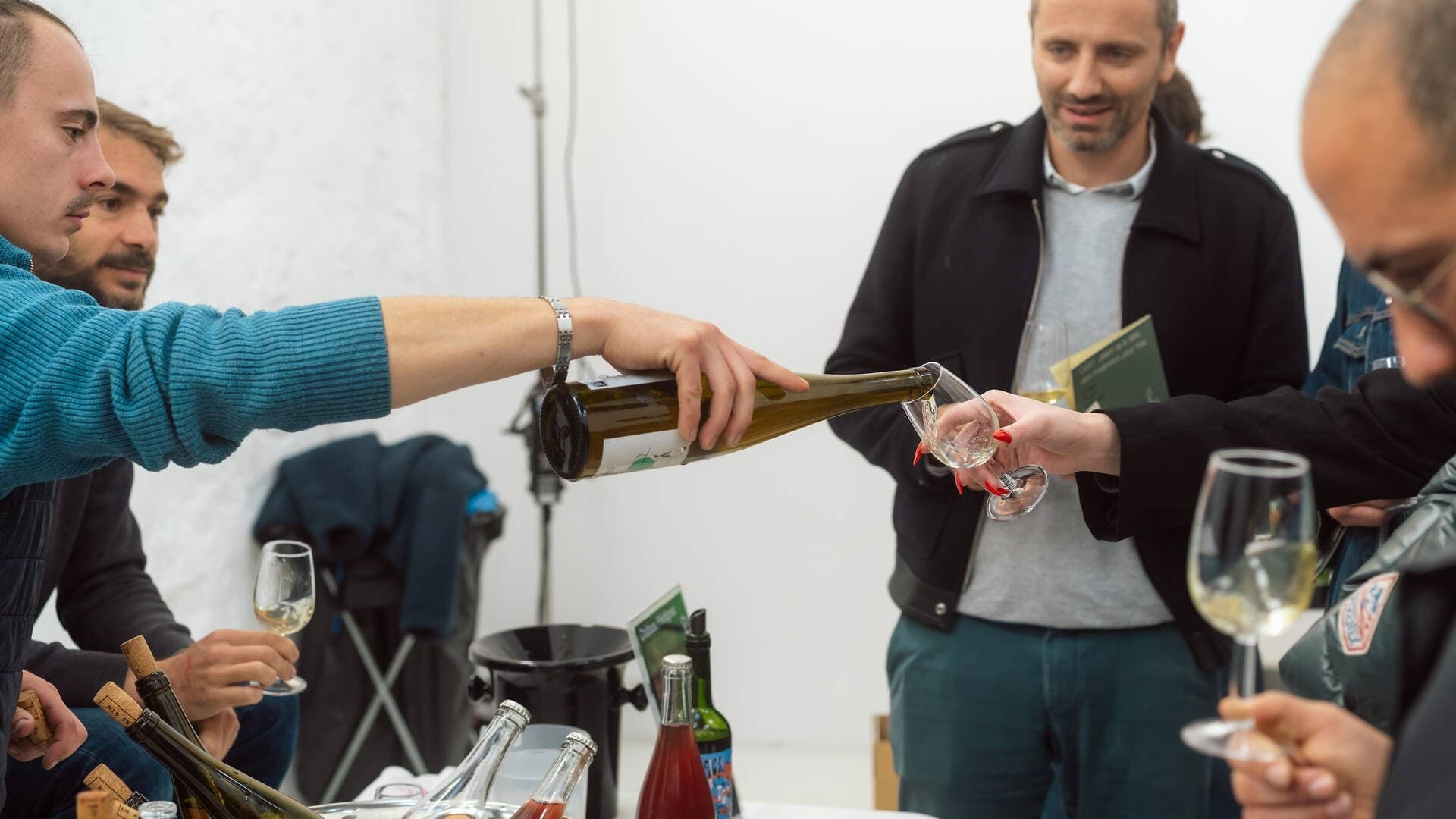 Un vigneron sert un vin blanc nature à des visiteurs verre tendu pendant le YARD Festival