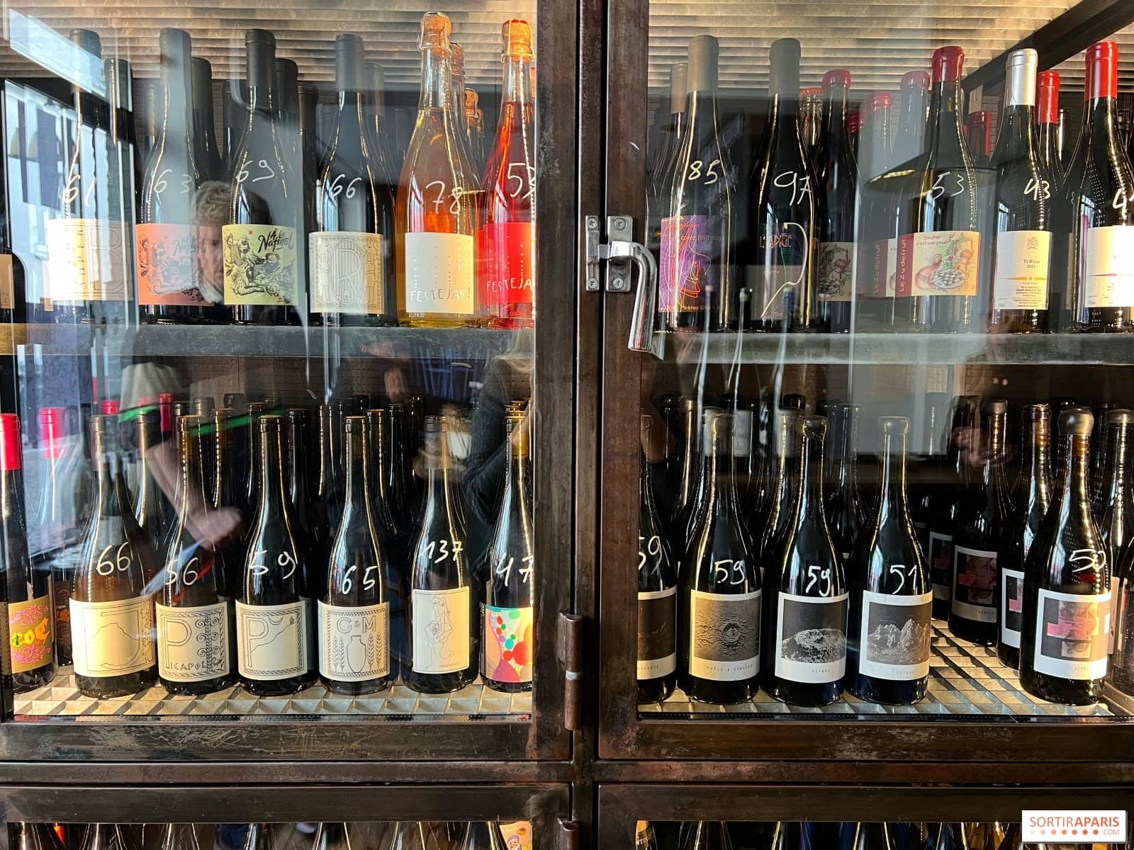 Armoire vitrée remplie de bouteilles de vin nature étiquetées à la craie chez YARD, rue de Mont-Louis